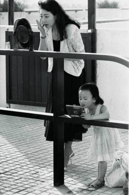 天性 王文扬 摄 1990 年，北京。时代的发展激发了人们对美的追求，这是正在街头补妆的女士和照镜子的小姑娘。