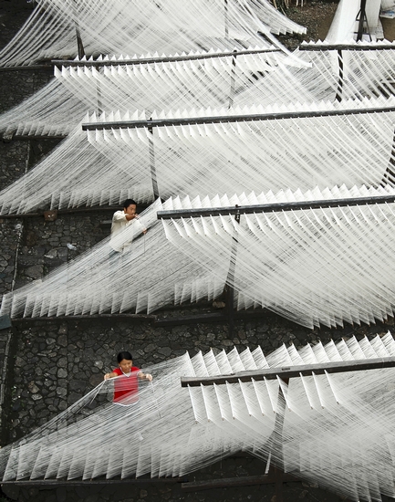 挂面 刘晓峰 摄 2010年，浙江省，在自家作坊前晾晒挂面的夫妇。