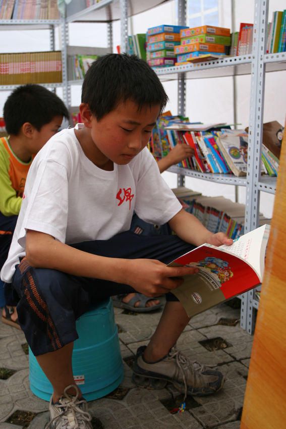 5月30日下午5点,一位小朋友在绵阳九洲体育馆受灾群众安置点的小型阅览室看书。中国文联网