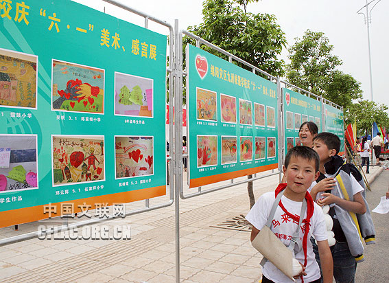 绵阳九洲体育馆,5月30日下午5点45,放学的九洲帐篷学校的孩子和家长从庆“六一”美术、感言展前走过。中国文联网