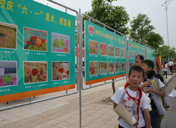 5月30日下午5点45,绵阳九洲体育馆,放学后的九洲帐篷学校的孩子和家长走过庆六一美术与感言展。中国文联网