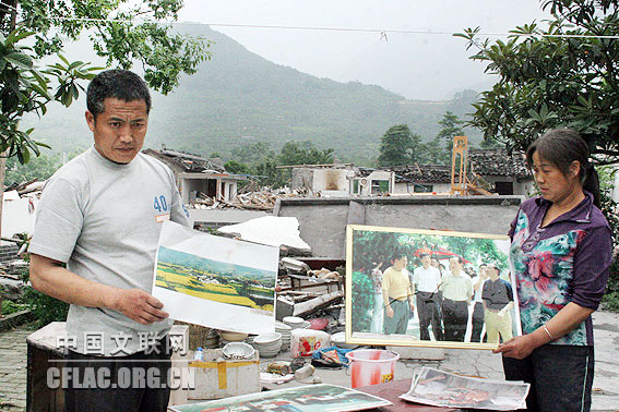 四川绵竹“年画村”棚花村村长唐福地(左)等向记者展示往日村庄风景秀美的照片。中国文联网